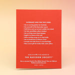 The back of the Never. Christmas Card on a pink and yellow background.