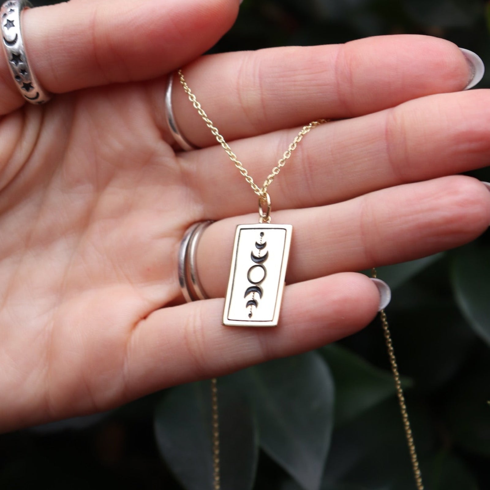 Someone holding the Star Tarot Gold Necklace, showing off the back.