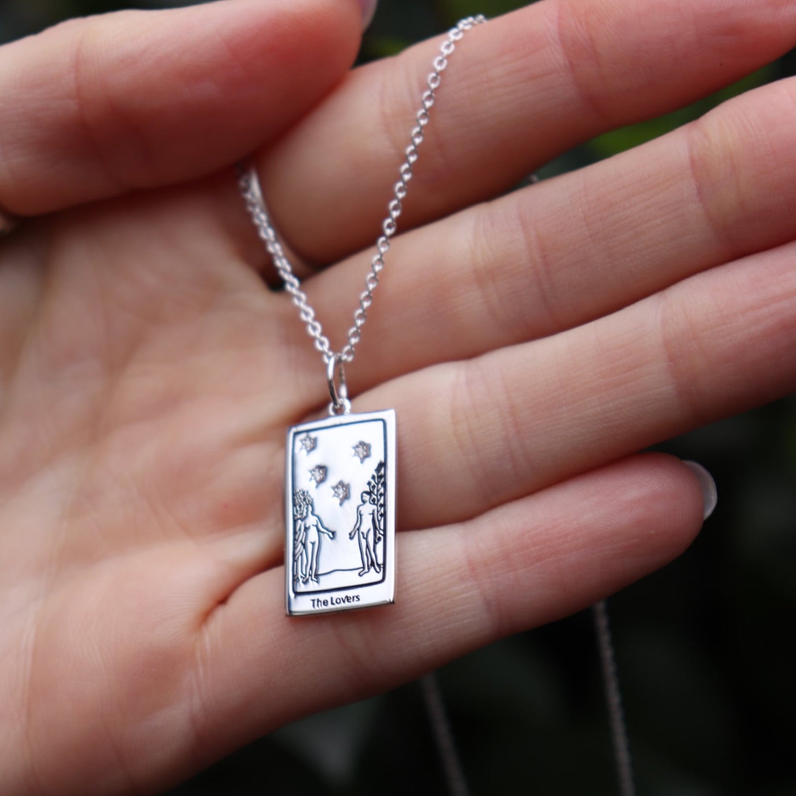 Someone holding the The Lovers Tarot Sterling Silver Necklace.