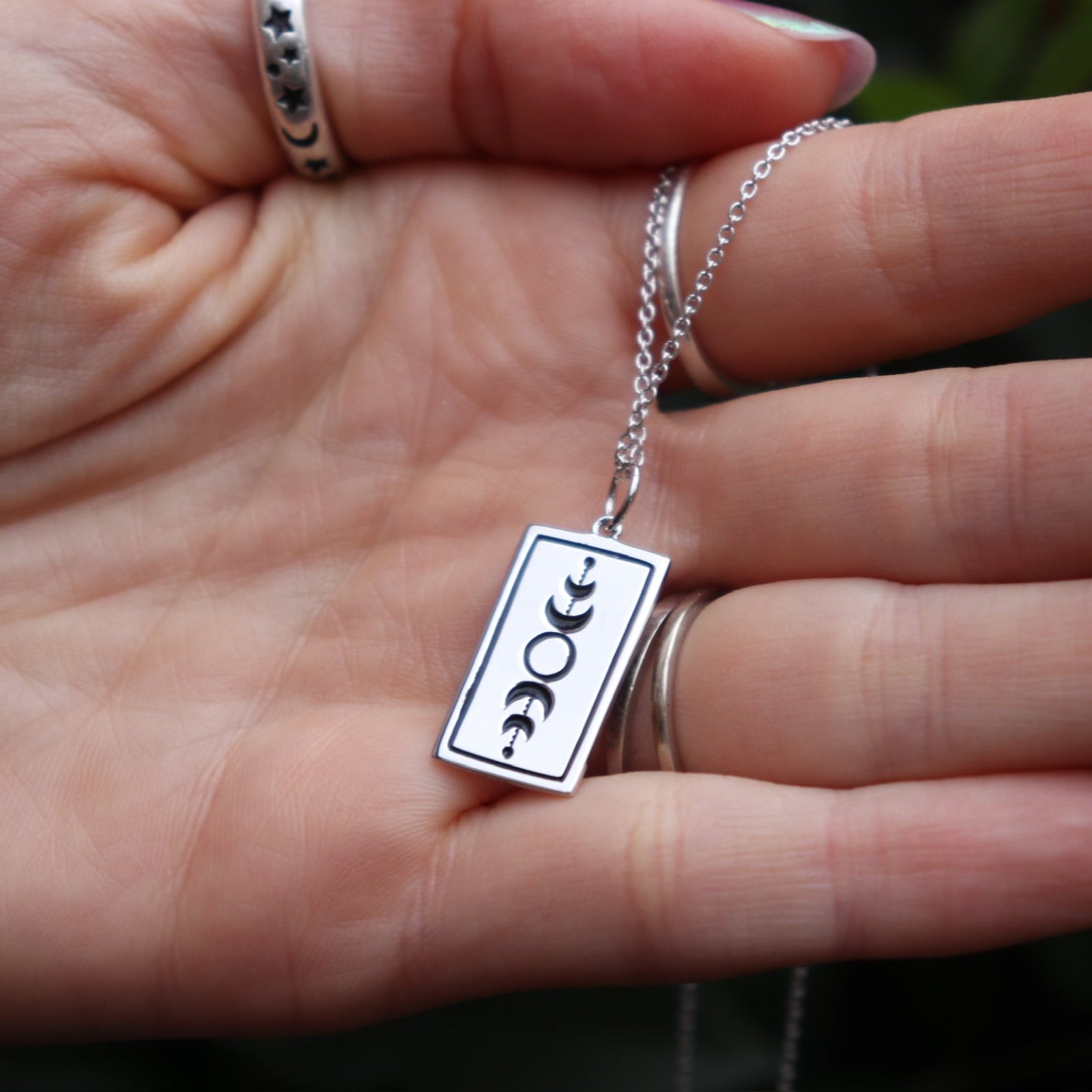 Someone holding the The Lovers Tarot Sterling Silver Necklace.