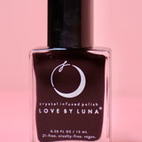 The Capricorn Zodiac Nail Polish with Micronized Garnet on a pink background.