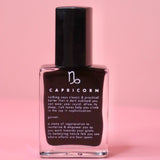 The Capricorn Zodiac Nail Polish with Micronized Garnet on a pink background.