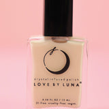 The Goddess Nail Polish with Micronized Rose Quartz, Selenite, & Moonstone on a pink background.