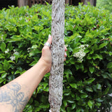 Someone holding the Jumbo Organic California White Sage - 20" Sage Smudge Stick in front of a green bush.