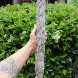 Someone holding the Jumbo Organic California White Sage - 20" Sage Smudge Stick in front of a green bush.