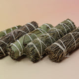 Bundles of sage on a pink and yellow background.