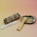 The contents of the Mini Smudge Kit with White Sage and Smudging Essentials box on a pink and yellow background.