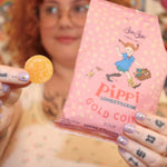 A woman holding the Pippi Longstocking Gold Coins bag with one candy in her left hand.