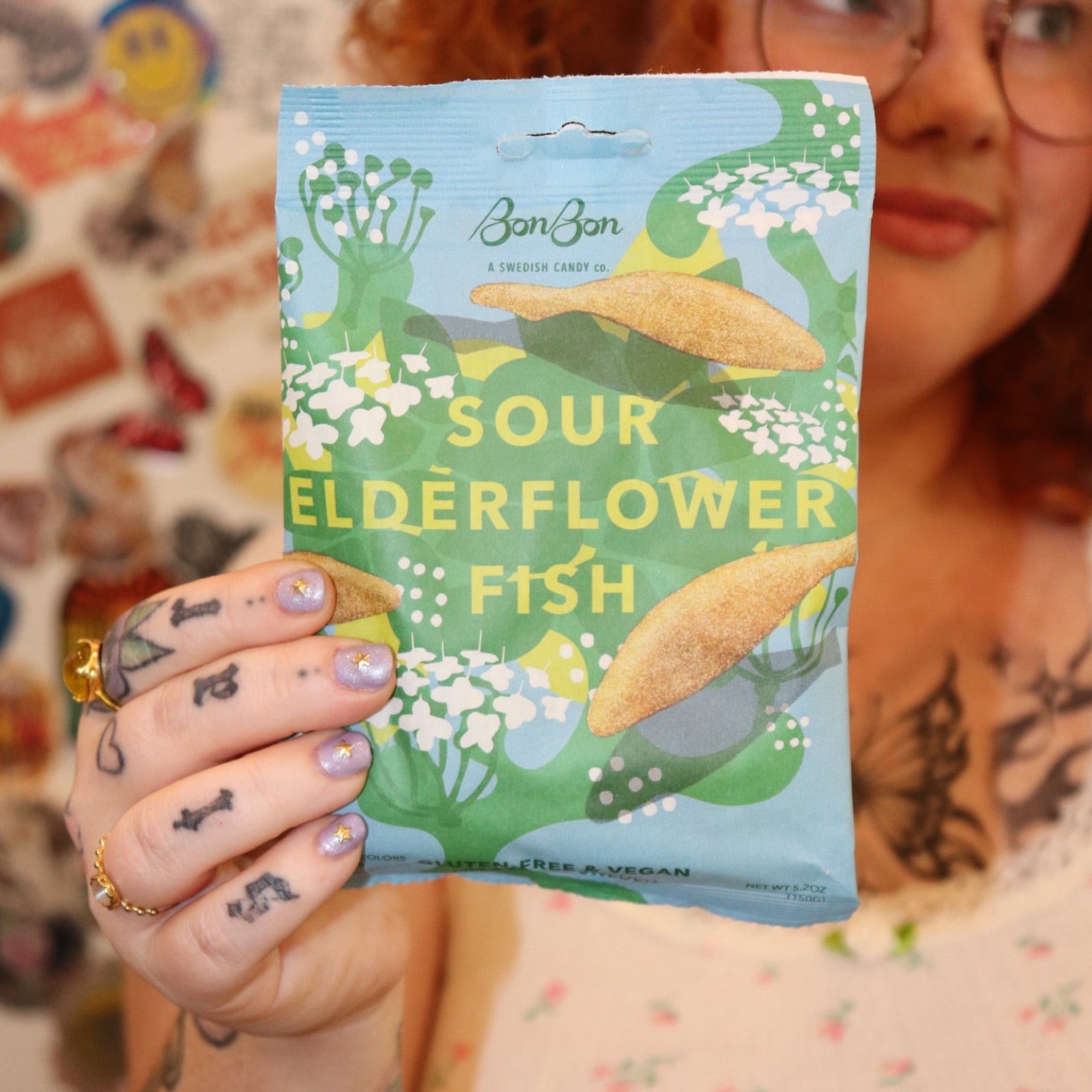 A woman holding a bag of the BonBon NYC Sour Elderflower Fish - Swedish Candy.