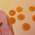 The Pippi Longstocking Gold Coins bag lying on a yellow surface with candies to the right of it.