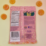 The Pippi Longstocking Gold Coins bag lying on a yellow surface with candies surrounding it.