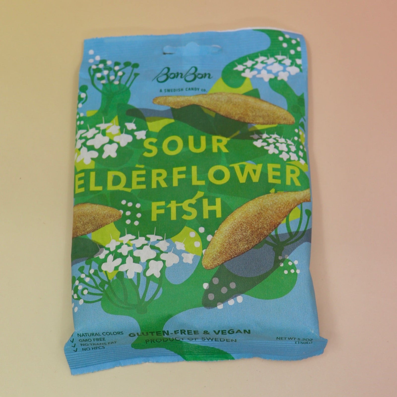 A bag of the BonBon NYC Sour Elderflower Fish - Swedish Candy on a pink and yellow background.