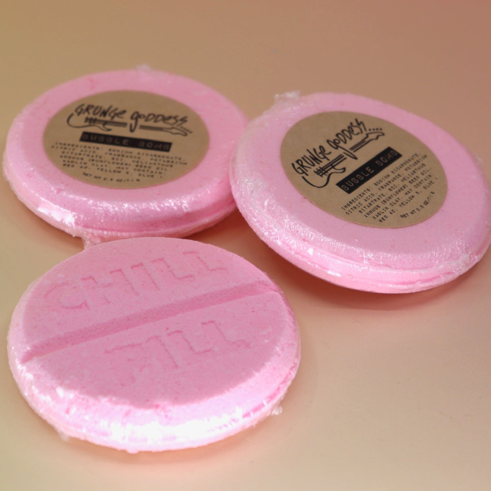Three Chill Pill Bubble Bath Bombs on a peach colored background.