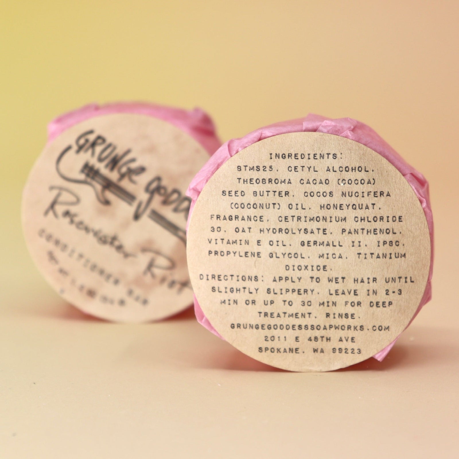 Two of the Rosewater Riot - Conditioner Bars, one showing off the back of the packaging, all on a peach-colored background.