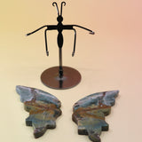 Two of the Natural Marine Jasper Butterfly Crystal with Stand on a pink and yellow background with the crystal butterfly wings off the stand.