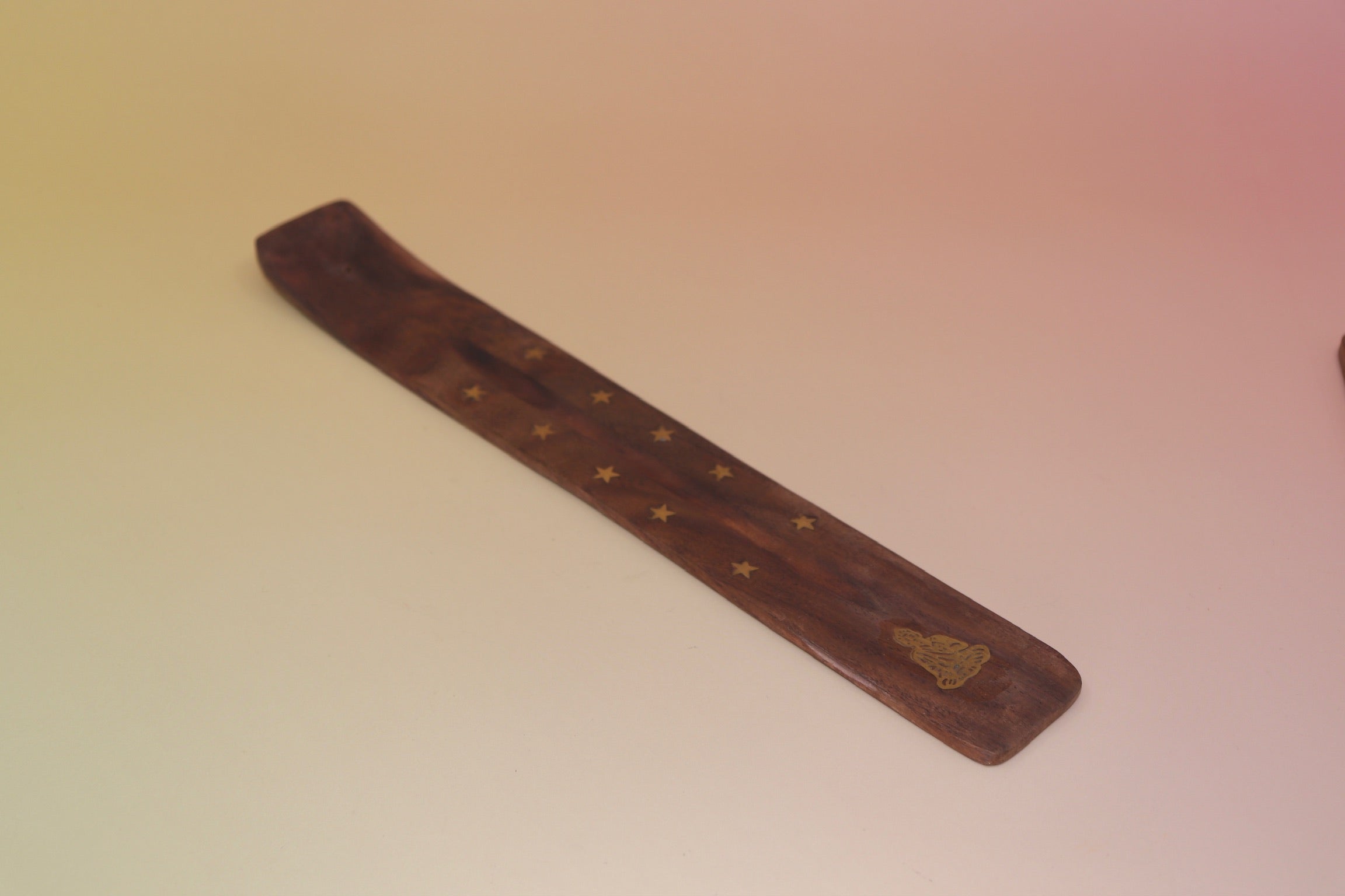 The Buddha Wooden Incense Burner on a pink and yellow background.