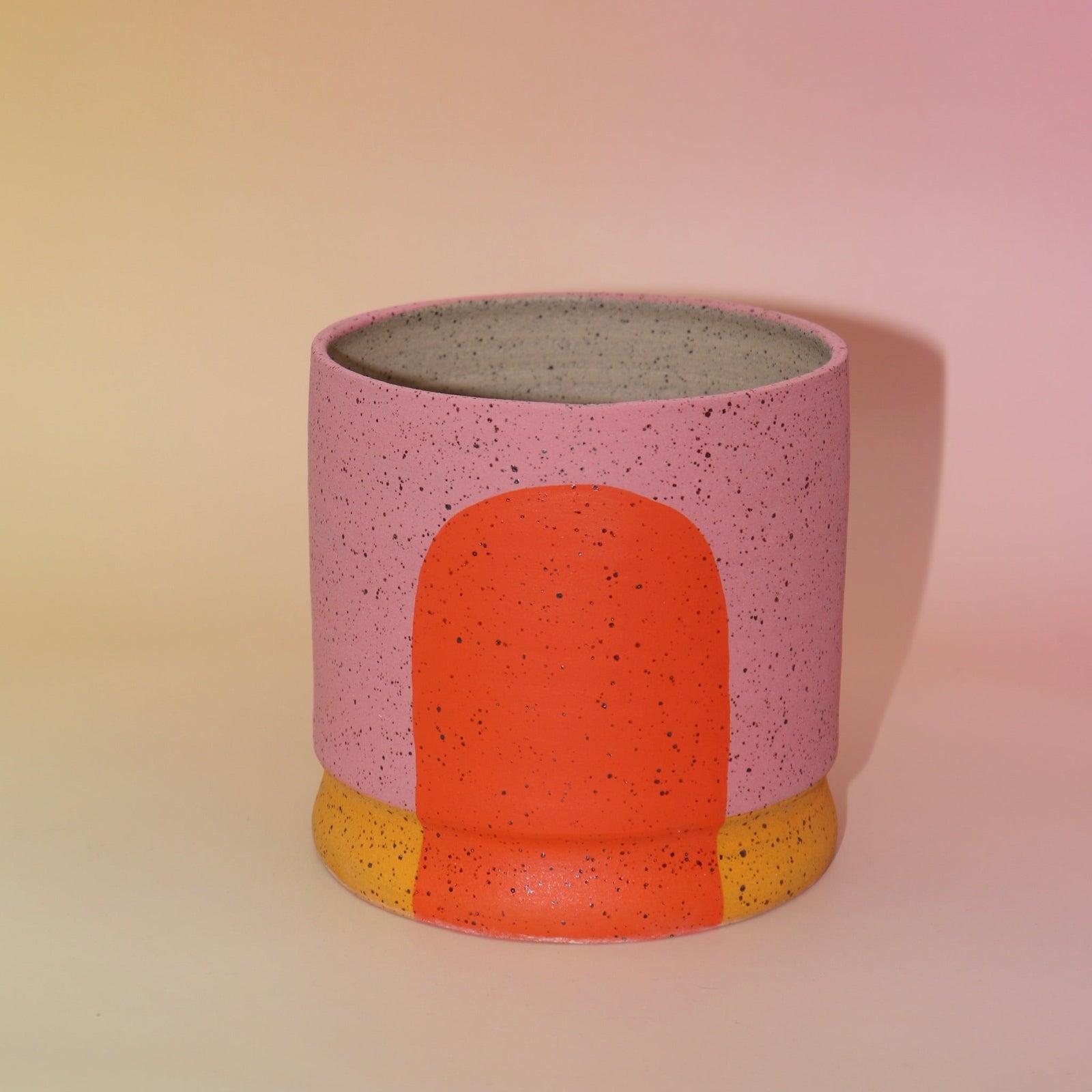 The Geraldine Multicolored Portal Stoneware 5 in. Planter on a pink and yellow background.