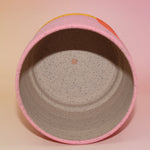 The Geraldine Multicolored Portal Stoneware 5 in. Planter on a pink and yellow background showing off the inside.