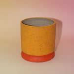 The Megan Multicolored Portal Stoneware 5 in. Planter on a pink and yellow background showing off the back.