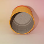 The Megan Multicolored Portal Stoneware 5 in. Planter on a pink and yellow background showing off the inside.