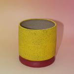 The Cordelia Multicolored Portal Stoneware 5 in. Planter on a pink and yellow background showing off the back.