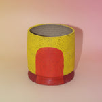 The Cordelia Multicolored Portal Stoneware 5 in. Planter on a pink and yellow background.