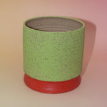 The Rosalie Multicolored Portal Stoneware 5 in. Planter on a pink and yellow background showing off the back.
