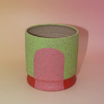 The Rosalie Multicolored Portal Stoneware 5 in. Planter on a pink and yellow background.