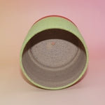 The Megan Multicolored Portal Stoneware 5 in. Planter on a pink and yellow background showing off the inside.