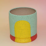 The Betty Multicolored Portal Stoneware 5 in. Planter on a pink and yellow background.