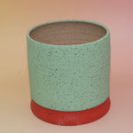 The Betty Multicolored Portal Stoneware 5 in. Planter on a pink and yellow background showing off the back.