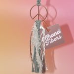 The sage Retro Peace Sign Car Charm on a pink background.