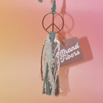 The sage Retro Peace Sign Car Charm on a pink background.