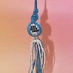 The blue Retro Disco Ball Macrame Car Charm on a pink background.