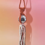 The orange Retro Disco Ball Macrame Car Charm on a pink background.