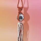 The orange Retro Disco Ball Macrame Car Charm on a pink background.