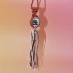 The orange Retro Disco Ball Macrame Car Charm on a pink background.