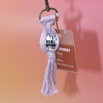 The lavender Mini Macrame Disco Ball Keychain on a pink background.