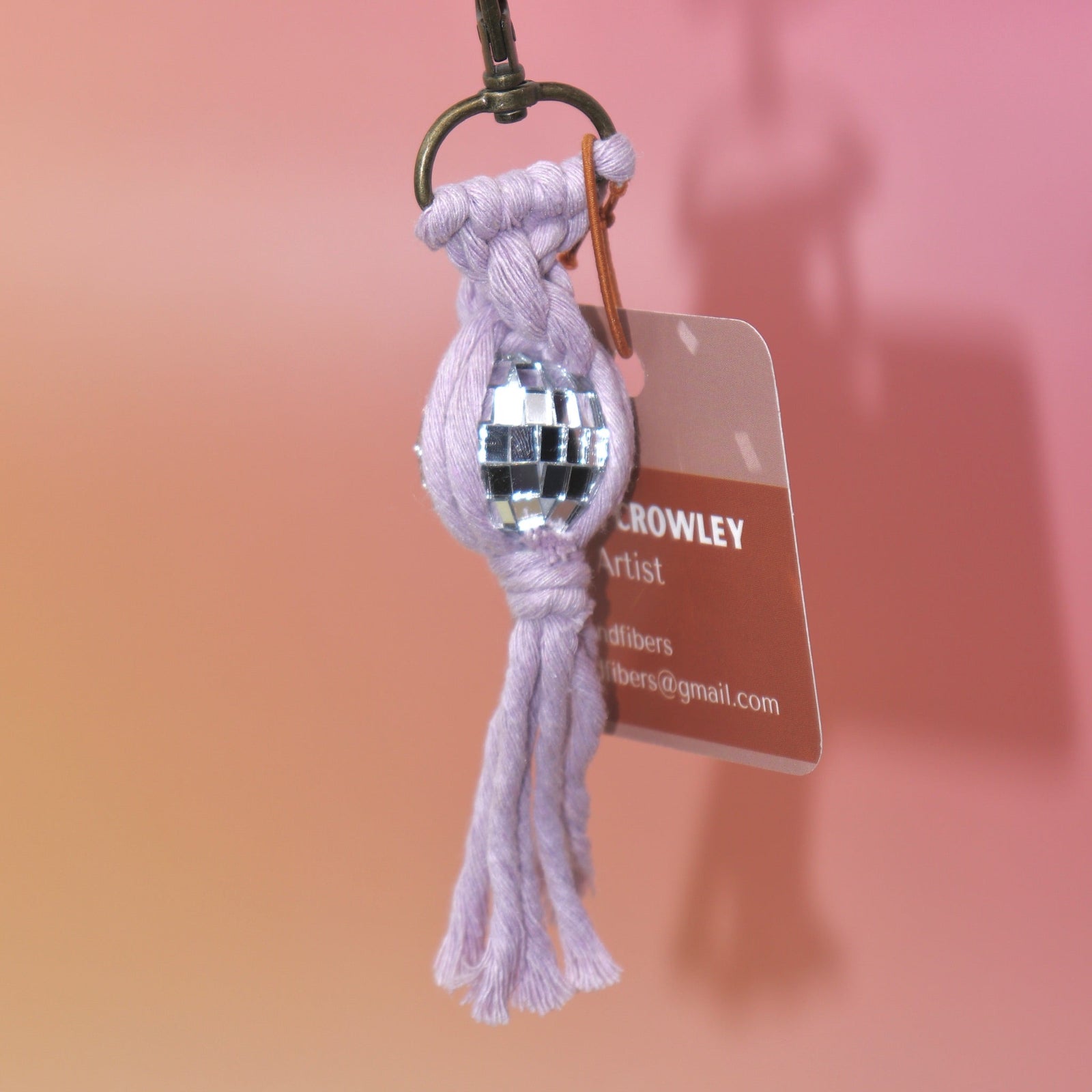 The lavender Mini Macrame Disco Ball Keychain on a pink background.