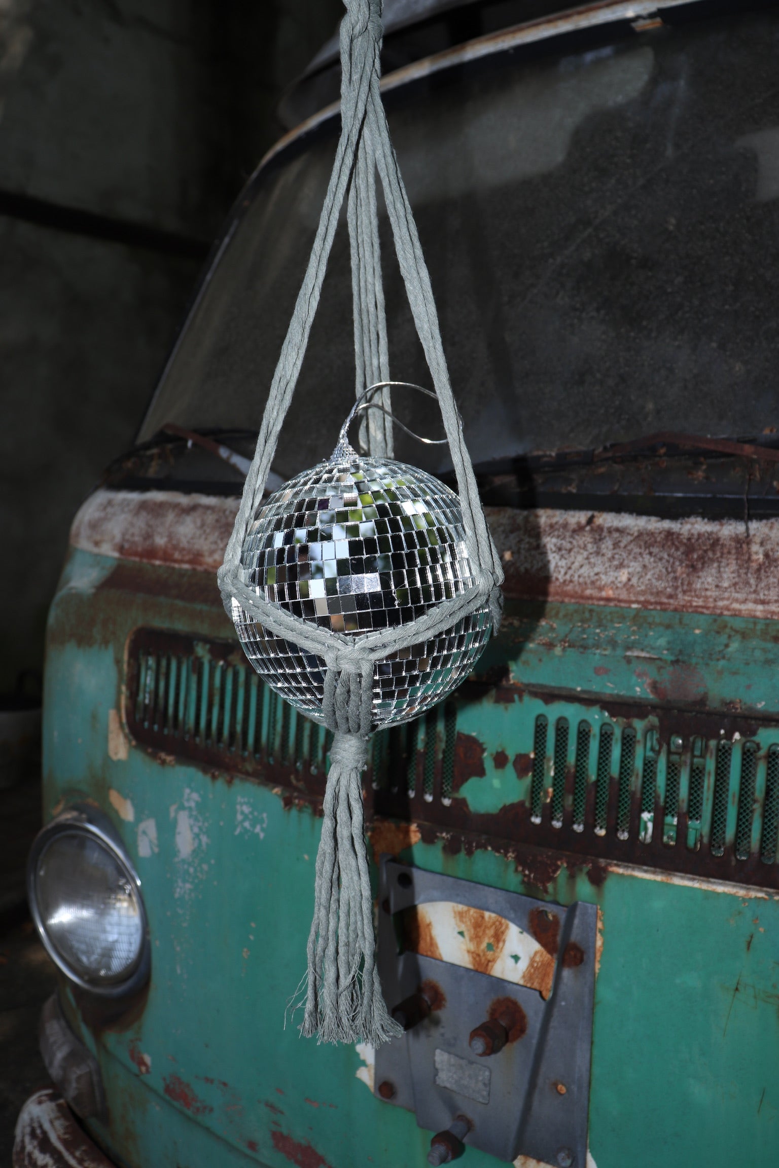 Someone holding the sage Disco Ball Hanger with Disco Ball in front of a vintage teal Volkswagen bus.