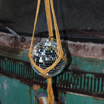 Someone holding the Mustard Disco Ball Hanger with Disco Ball in front of a vintage teal Volkswagen bus.