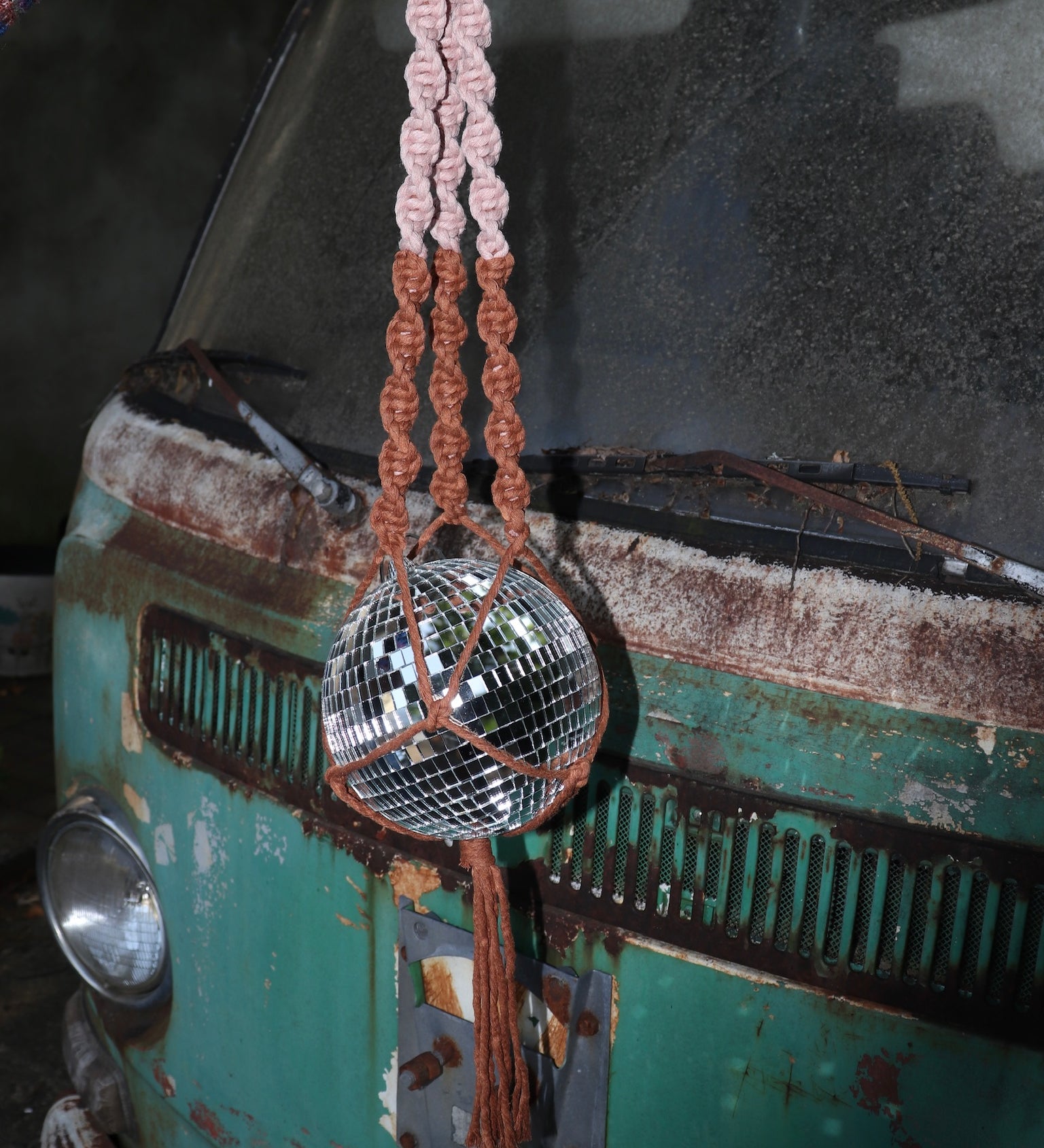 Someone holding the blush and rust Color Dip Disco Ball Hanger - Macrame Plant Hanger in front of a vintage teal Volkswagen bus.