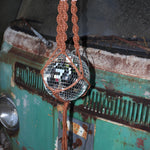 Someone holding the blush and rust Color Dip Disco Ball Hanger - Macrame Plant Hanger in front of a vintage teal Volkswagen bus.