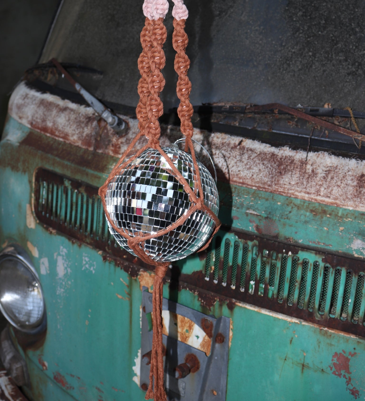 Someone holding the blush and rust Color Dip Disco Ball Hanger - Macrame Plant Hanger in front of a vintage teal Volkswagen bus.