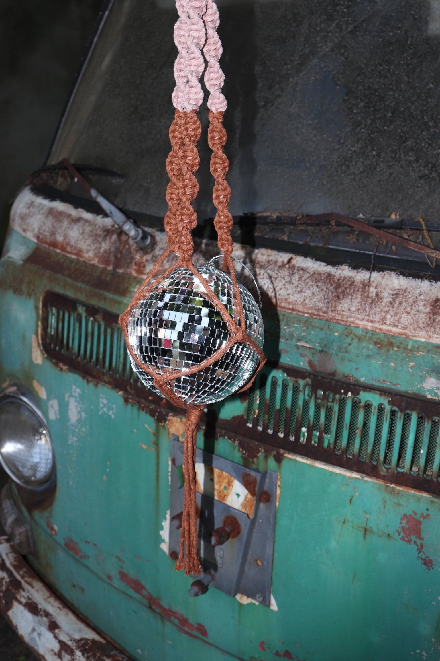 Someone holding the blush and rust Color Dip Disco Ball Hanger - Macrame Plant Hanger in front of a vintage teal Volkswagen bus.