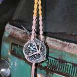 Someone holding the blush and mustard Color Dip Disco Ball Hanger - Macrame Plant Hanger in front of a vintage teal Volkswagen bus.