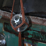 Someone holding the Rust Disco Ball Hanger with Disco Ball in front of a rusted teal Volkswagen bus.