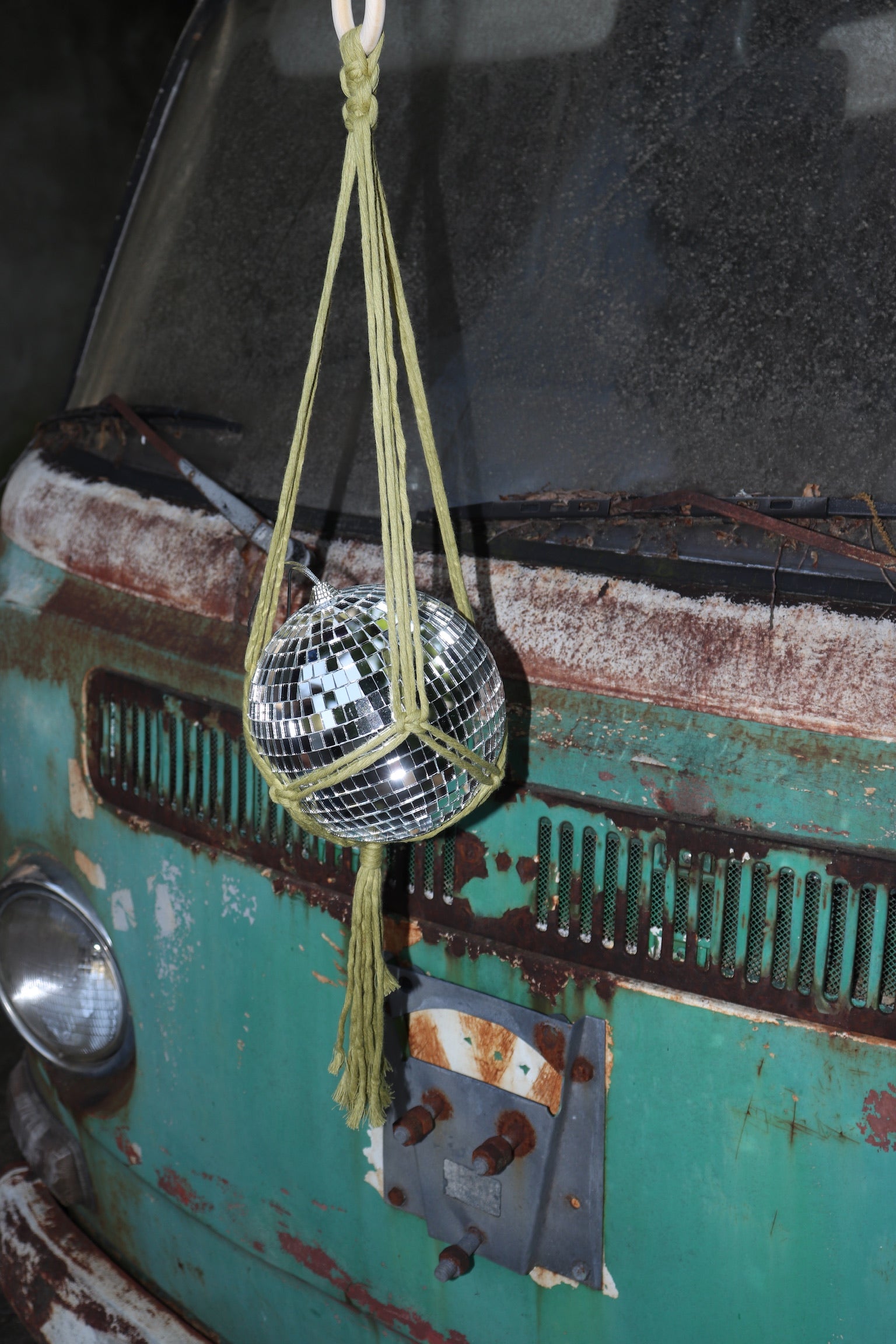 Someone holding the Chartreuse Disco Ball Hanger with Disco Ball in front of a vintage teal Volkswagen bus.