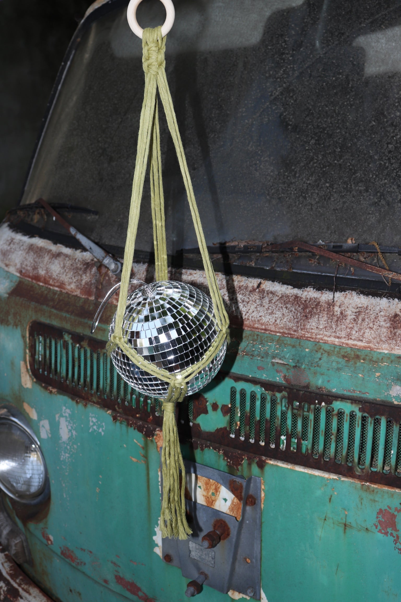 Someone holding the Chartreuse Disco Ball Hanger with Disco Ball in front of a vintage teal Volkswagen bus.