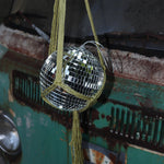 Someone holding the Chartreuse Disco Ball Hanger with Disco Ball in front of a vintage teal Volkswagen bus.